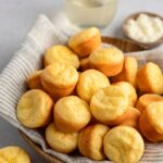 Brazilian cheese bread in basket with linen napkin and glass of wine