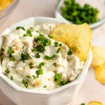 French onion dip in white bowl with potato chips