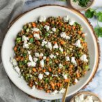 lentil salad in bowl with linen napkin and small bowls of parsley and goat cheese