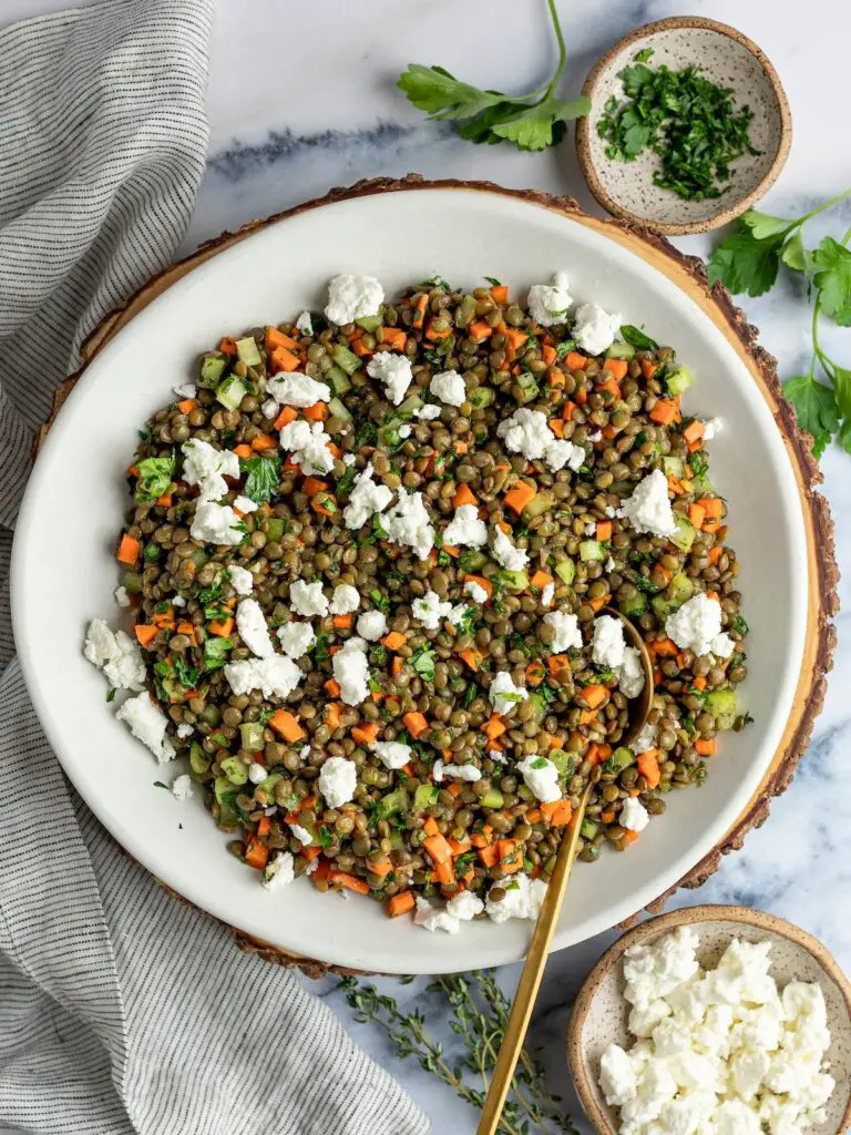 lentil salad in bowl with linen napkin and small bowls of parsley and goat cheese