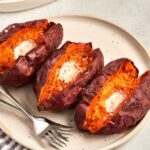 baked sweet potatoes with butter on platter with dish towel