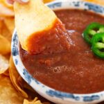 Dipping tortilla chip into salsa.