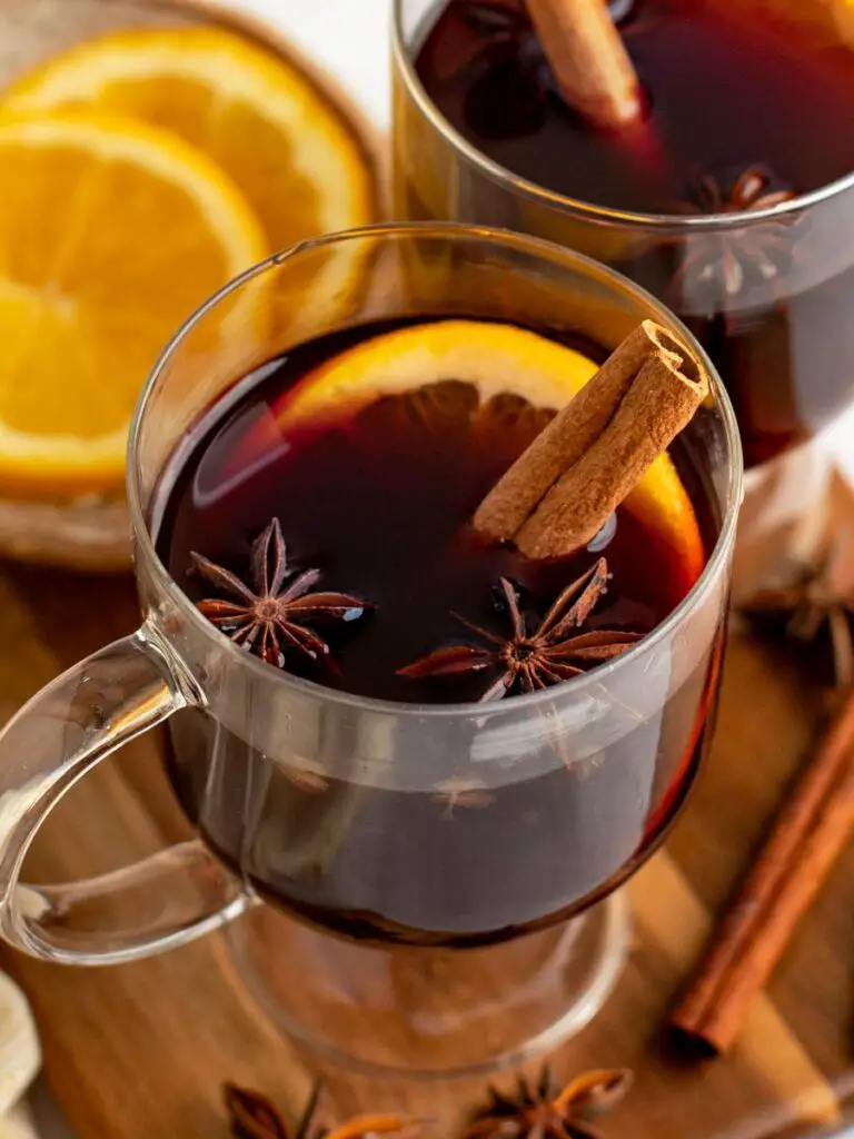 mugs of mulled wine with cinnamon sticks, orange slices and spices.