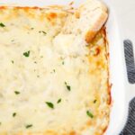 Baked artichoke dip in a white dish.