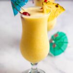 finished pina colada with umbrella, maraschino cherry, and fresh pineapple garnishes